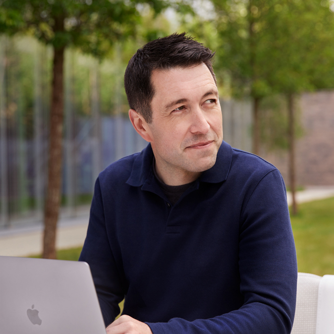 Nahaufnahme von Rob, der draussen am offenen Laptop sitzt.
