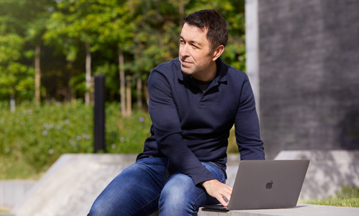 Rob sitzt draussen und arbeitet an seinem Laptop.