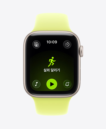 실외 달리기 운동 화면이 열린 상태로 화면 하단에는 Apple Music 재생 제어 항목이 보이는 스타라이트 색상 알루미늄 케이스의 Apple Watch SE 3, 그리고 네온 옐로 색상 스포츠 밴드